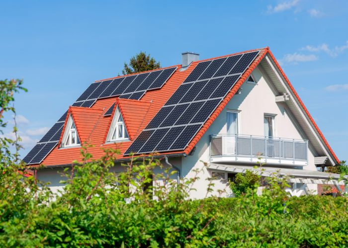Solaranlage auf Hausdach mit roten Ziegeln und grüner Umgebung
